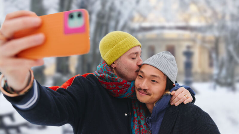 Två män tar en selfie och ger varandra en puss i Engelska parken