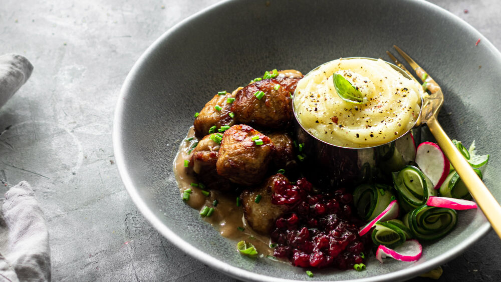 En tallrik med köttbullar, potatismos, gräddsås och lingonsylt