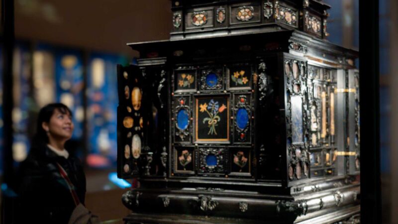 Kvinna kolla på en museemonter med Konstskåpet, Gustavianum, Uppsala