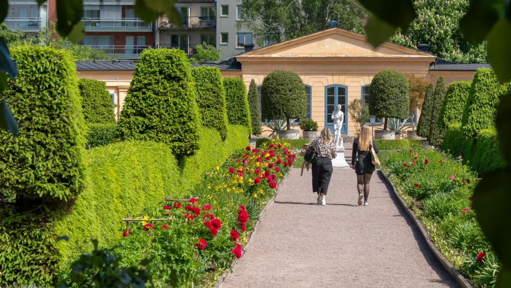 Två kvinnor promenerar i trädgård