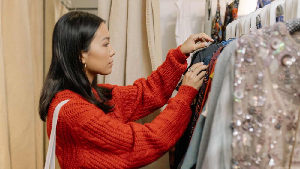 En kvinna bläddrar bland second hand kläder