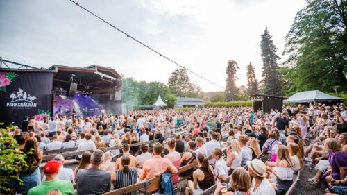 Bild på publik framför en utomhusscen under en sommarkväll