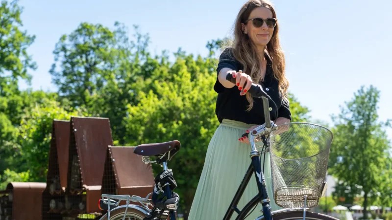 Kvinna leder en cykel i Uppsalas parker