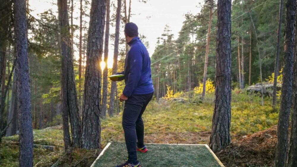 Man spelar disc golf i skogen