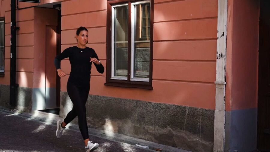 Kvinna springer med vy över byggnad i Uppsala
