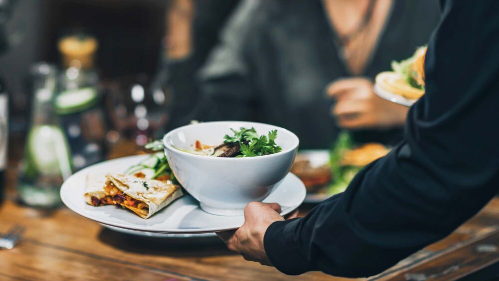 En tallrik med soppa bärs av en servitör