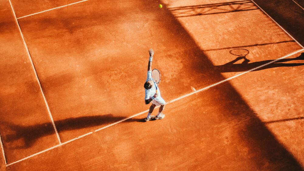 Man spelar tennis på en tennisplan