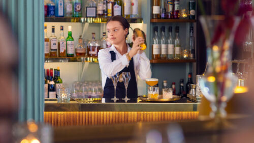En bartender skakar en drink bakom bardisk