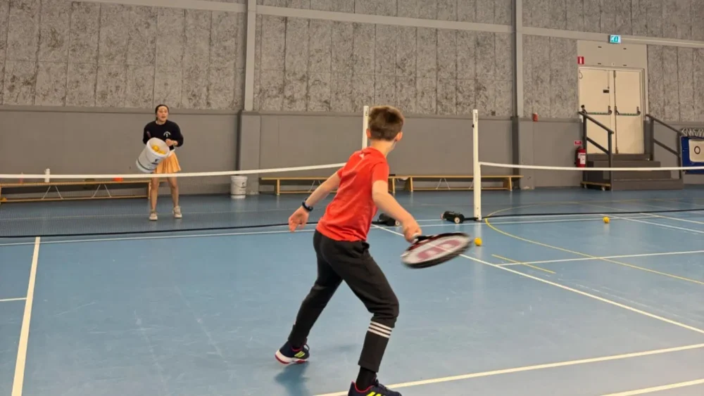 Barn som spelar tennis med en tränare