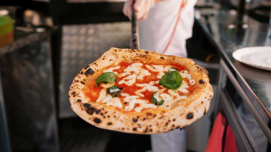 Närbild på en pizzabagare med pizza
