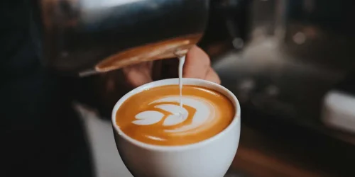 En man häller upp mjölk i kaffe