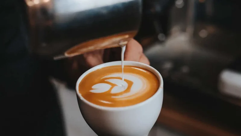 En man häller upp mjölk i kaffe