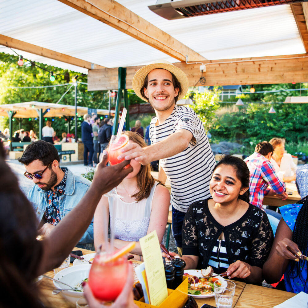Människor som äter middag utomhus under ett parasoll