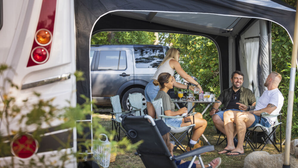 Människor sitter i förtält till husvagn