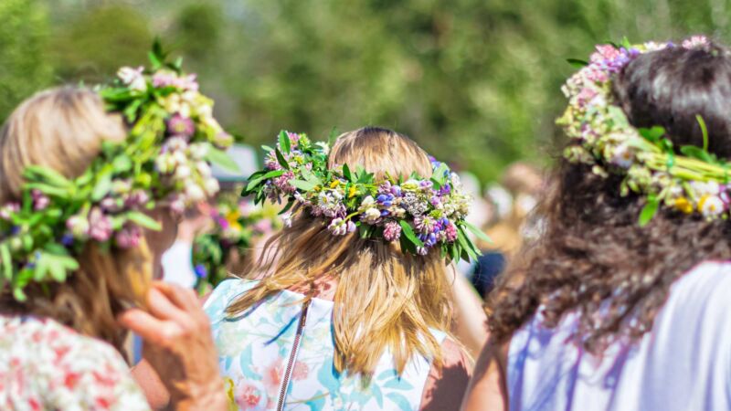 Tre kvinnor med midsommarkrans på huvudet