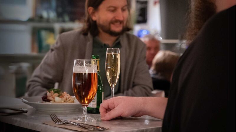 Två vänner äter mat i Saluhallen i Uppsala