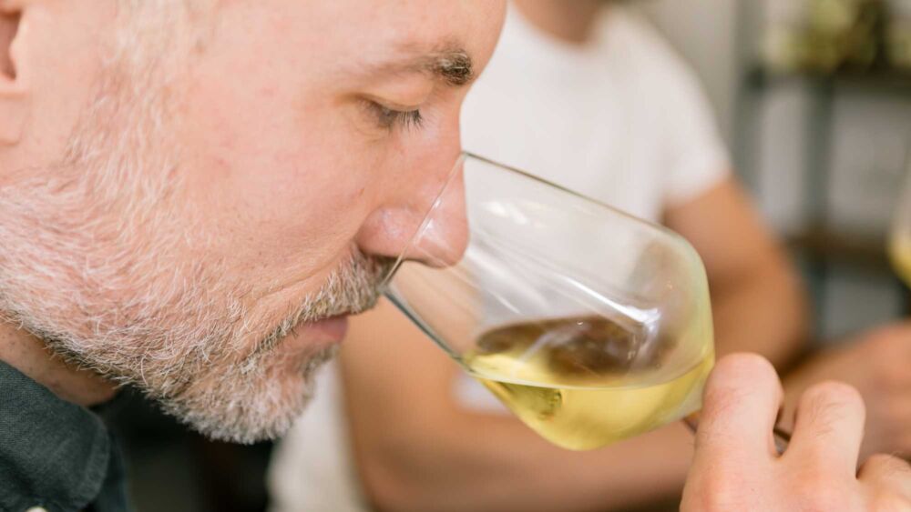 En man luktar i ett glas med vitt vin på en mässa