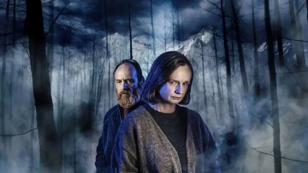 Två skådespelare framför en mörk skog