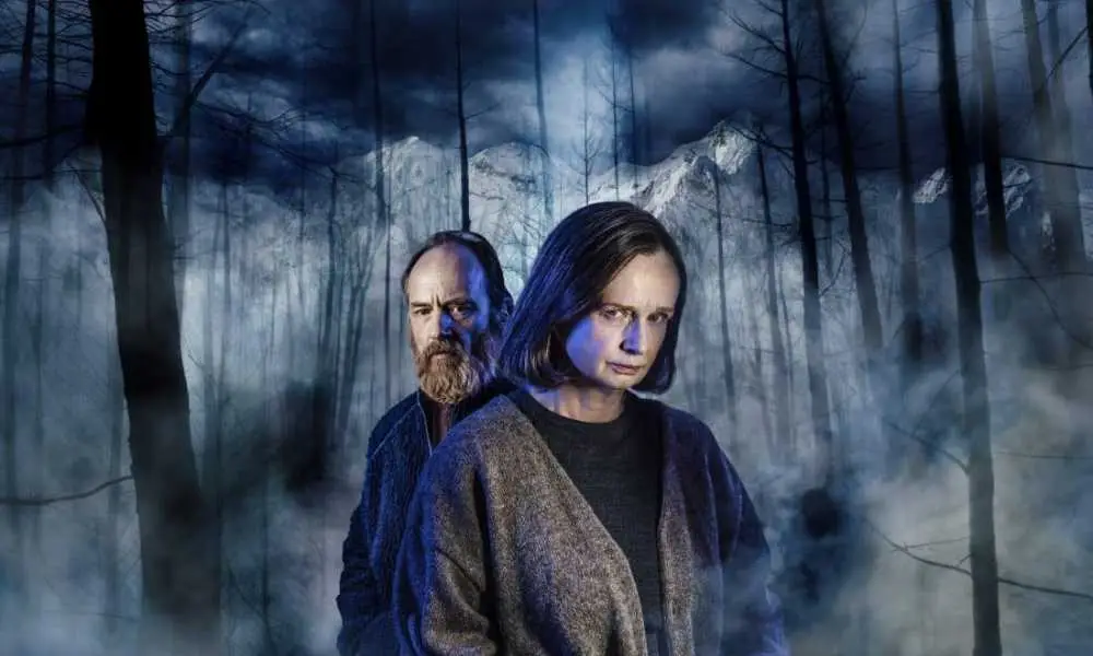 Två skådespelare framför en mörk skog