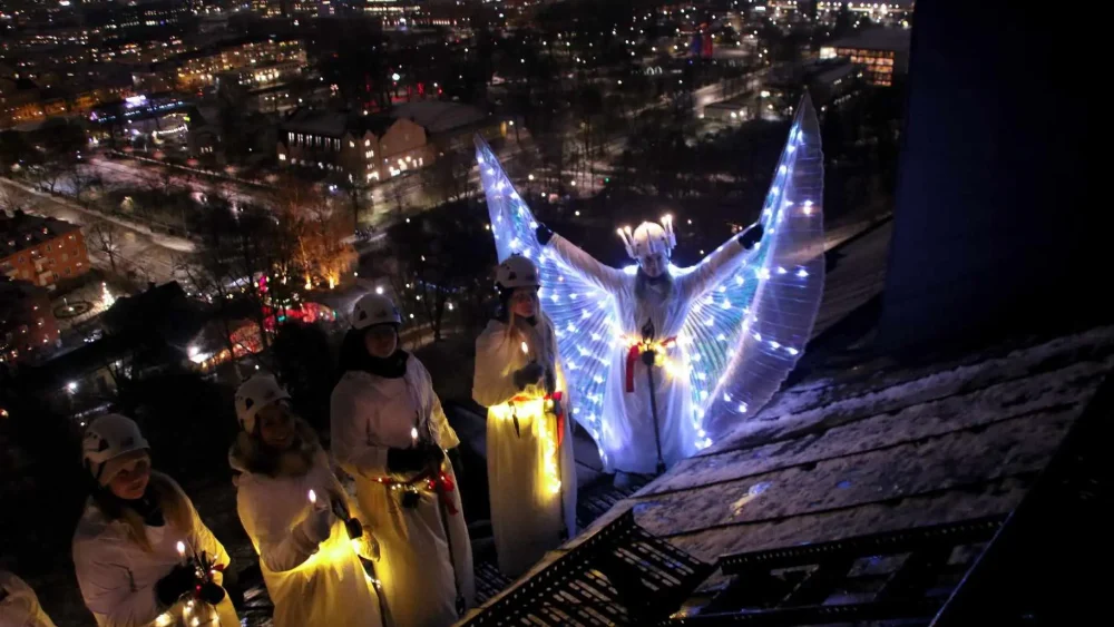 En lucia med lysande dräkt står på slottstaket