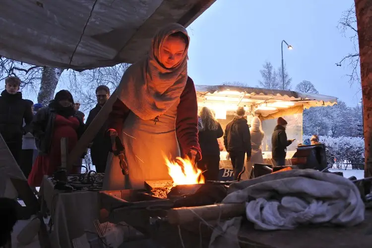 En kvinna vid en eld på en julmarknad