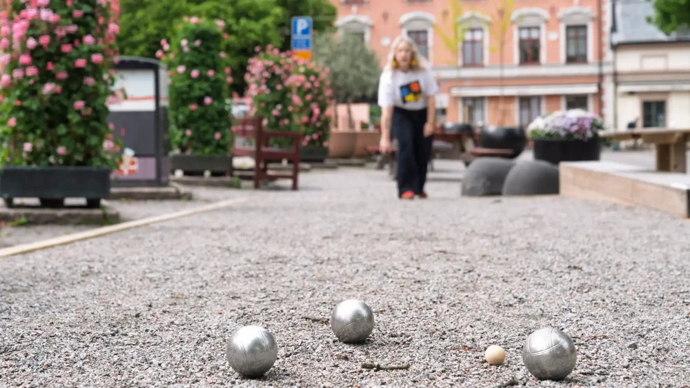 Kvinna som spelar boule på e grusplan