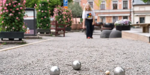 Kvinna som spelar boule på e grusplan