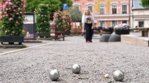 Kvinna som spelar boule på e grusplan