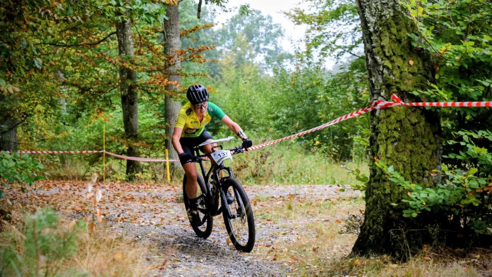 Kvinna cyklar i skog